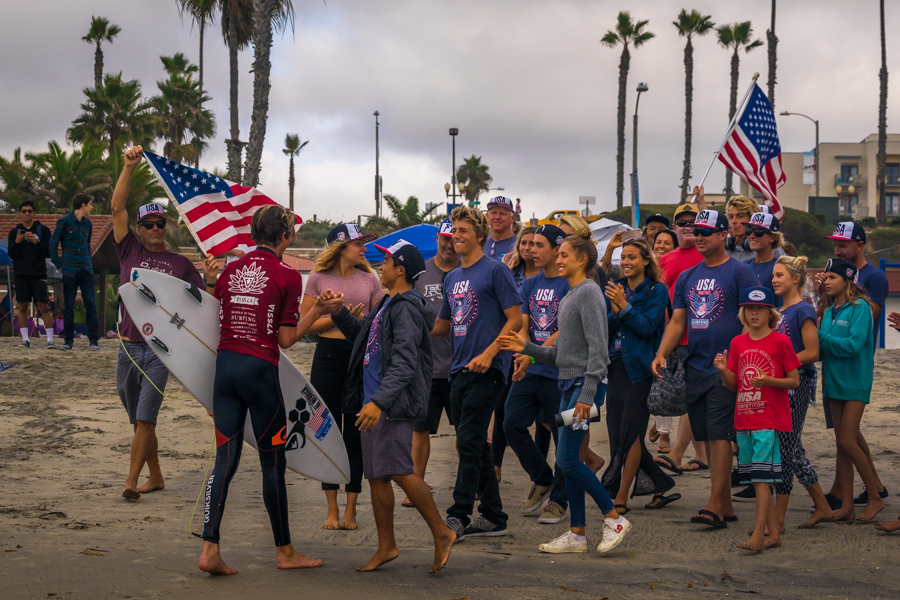 Team USA, the overall points leader, greets John Mel on the beach after his heat win. Photo: ISA/Sean Evans